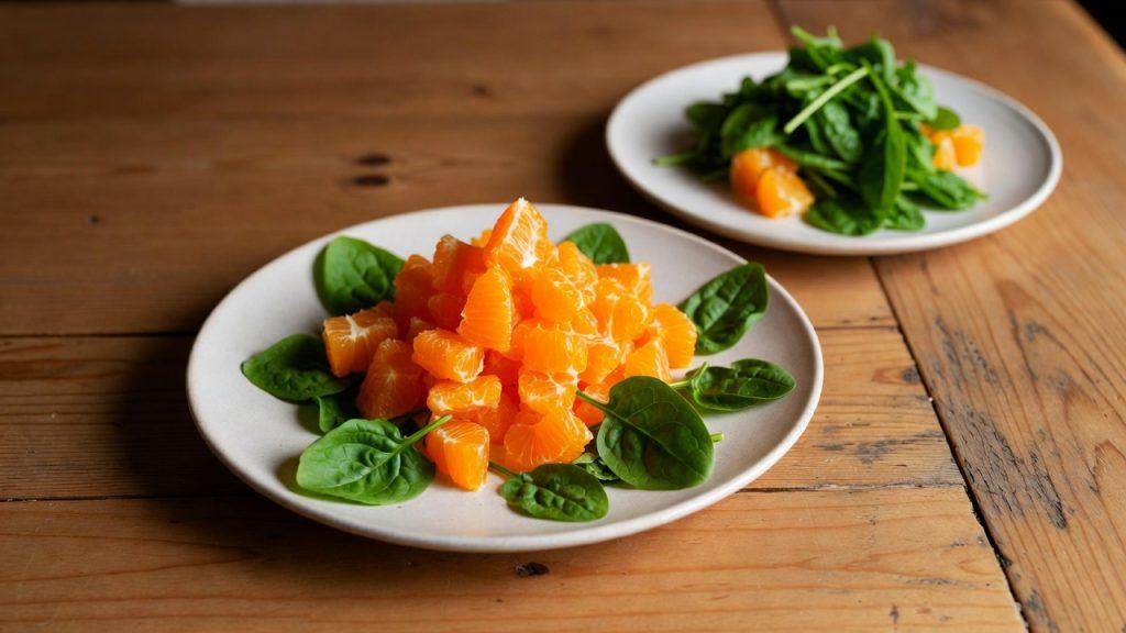 Farfurie cu citrice proaspete (portocale) și frunze de spanac bogate în vitamina C și K pentru vindecarea rapidă a vânătăilor
